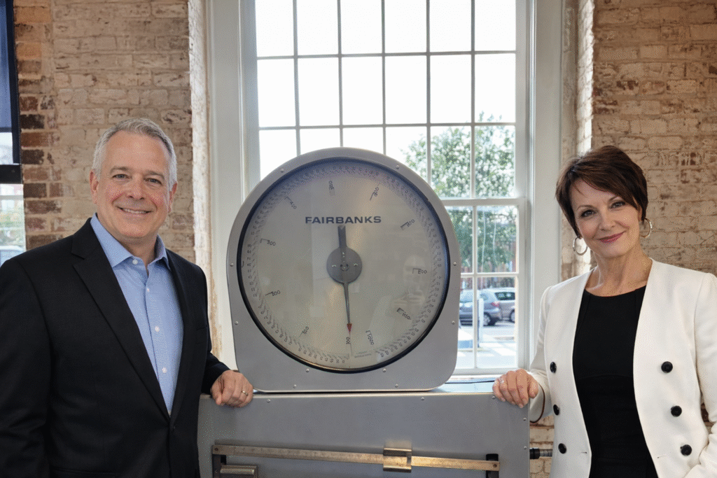 Fred McDaniel, Ph.D., Chief Academic Officer, and Melody Schopp, Ph.D., Vice President for Government Relations, flank the industrial scale in the MetaMetrics' office in Durham, NC. Original to the building, today this scale is a nod to the Lexile and Quantile scales for measuring reading and math, developed by MetaMetrics.