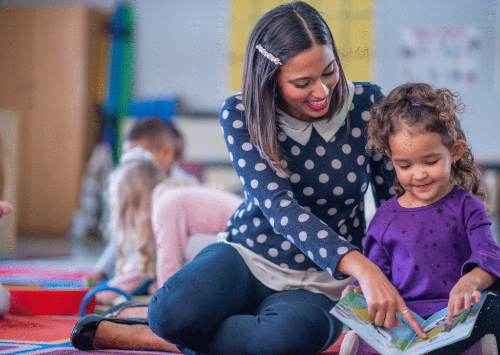 A kindergarten teacher works one-on-one with a student learning to read.