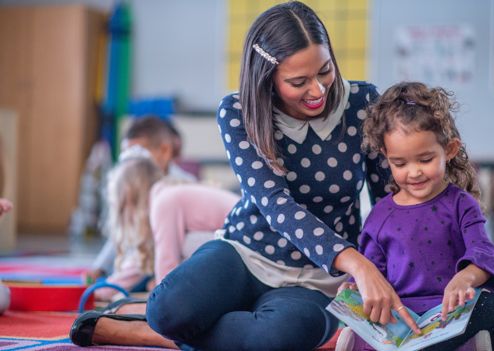 A kindergarten teacher works one-on-one with a student learning to read.